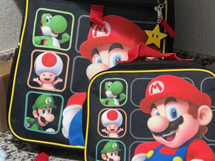 two mario backpacks and lunchbox on top of the table