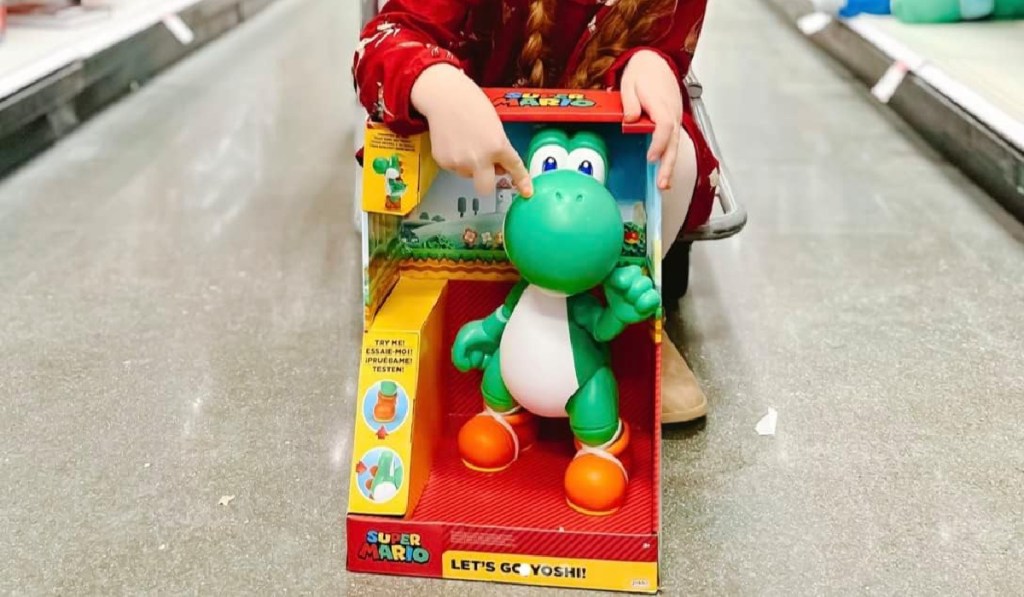 little girl bending down and pointing at a nintendo yoshi figure
