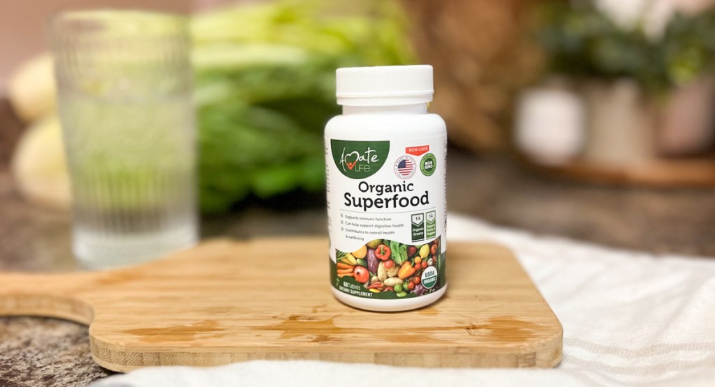 organic superfood bottle displayed on a cutting board with water and veggies in the background