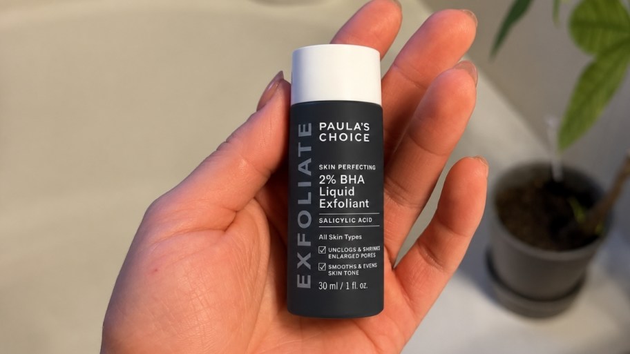 a womans hand holding a bottle of paulas choice BHA exfoliant