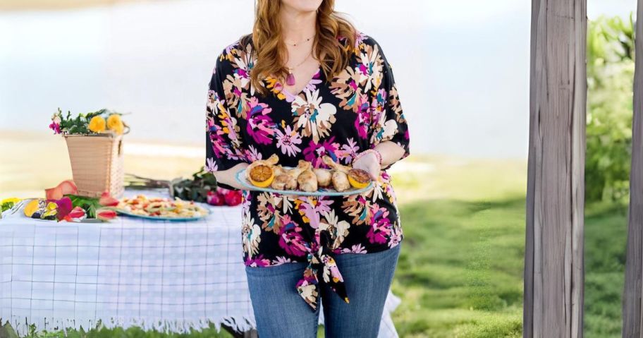 woman wearing the pioneer woman blouse outside holding a tray of food