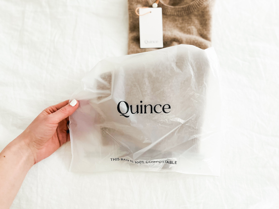 hand holding quince compostable packaging with sweater inside