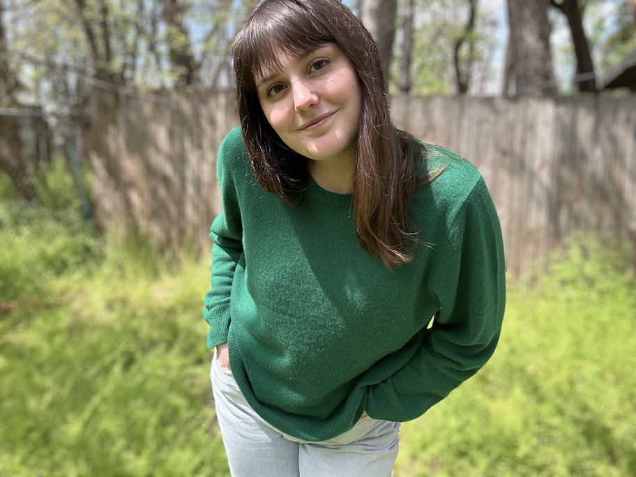 woman wearing dark green cashmere sweater outside in grass