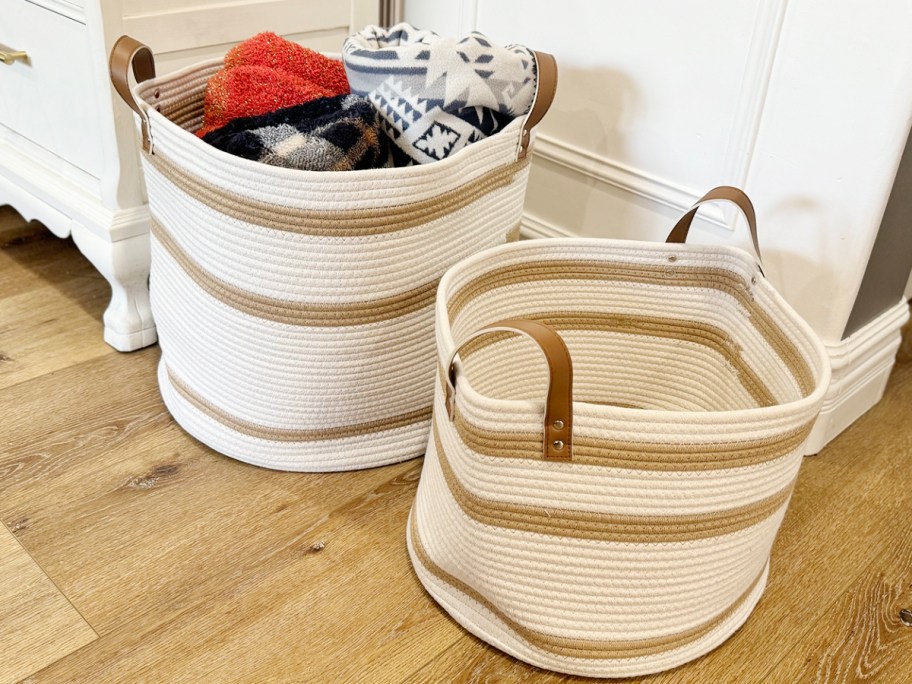 beige and tan rope basket with blankets inside with smaller basket next to it