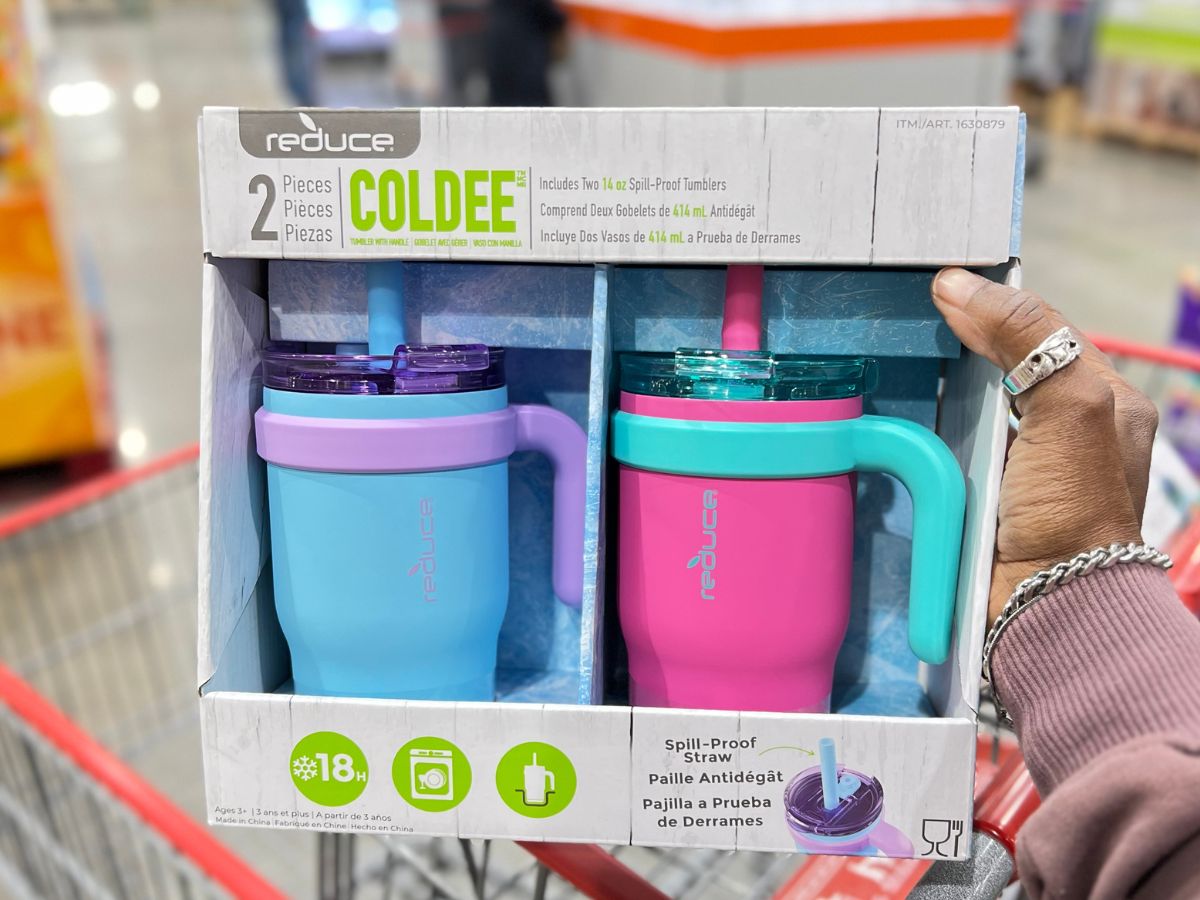 a womans hand displaying a 2-pack of reduce coldee tumblers in pink color combo, in a costco store