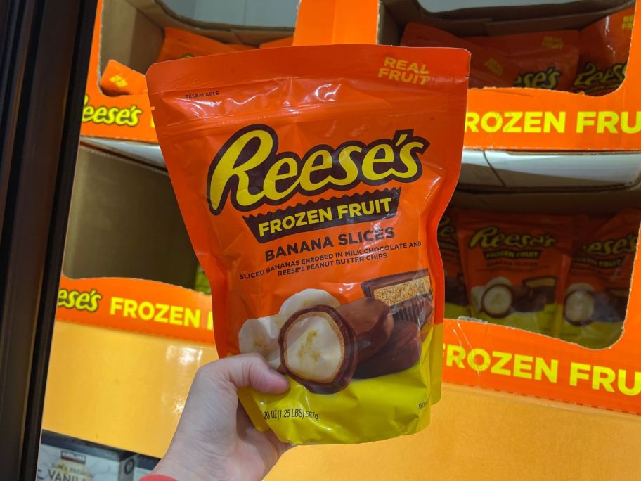 a womans hand holding up a bag of reese's frozen friut.