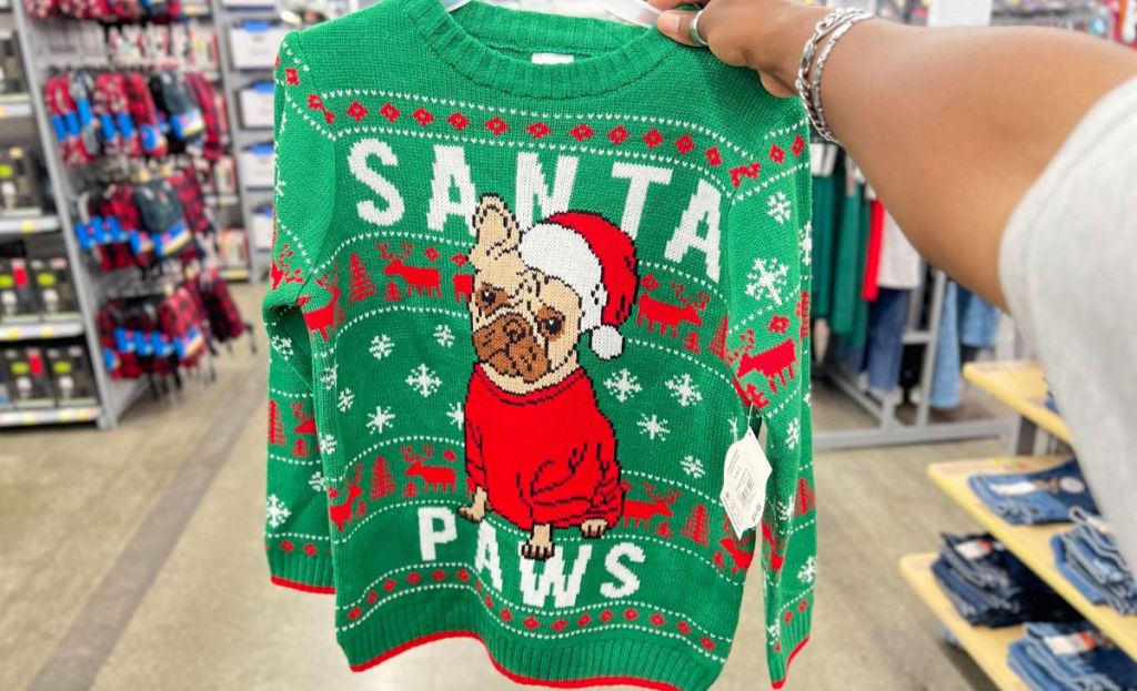 christmas sweater with dog on front being held up in store