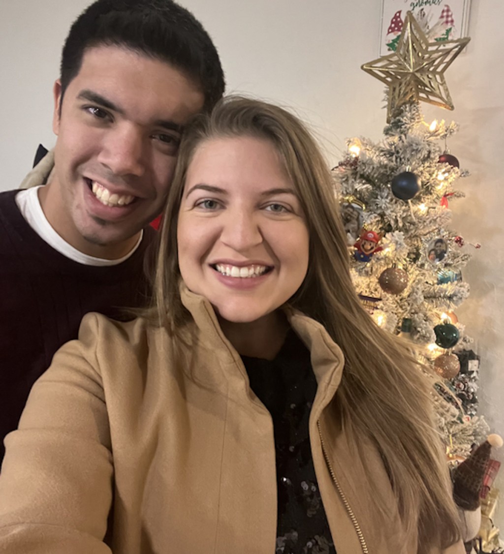 man and woman taking selfie in front of christmas tree