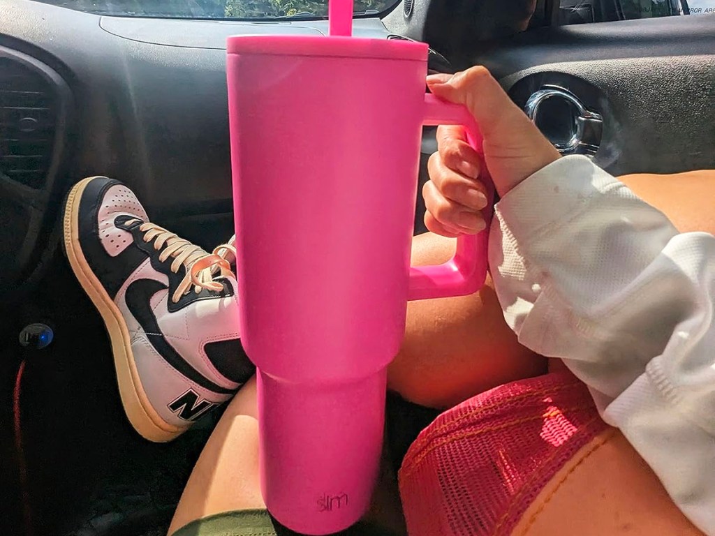 hand holding hot pink tumbler in car