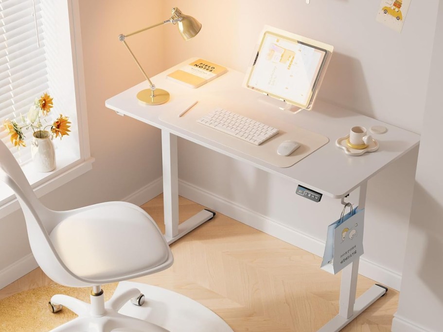 white electric standing desk with computer and office accessories