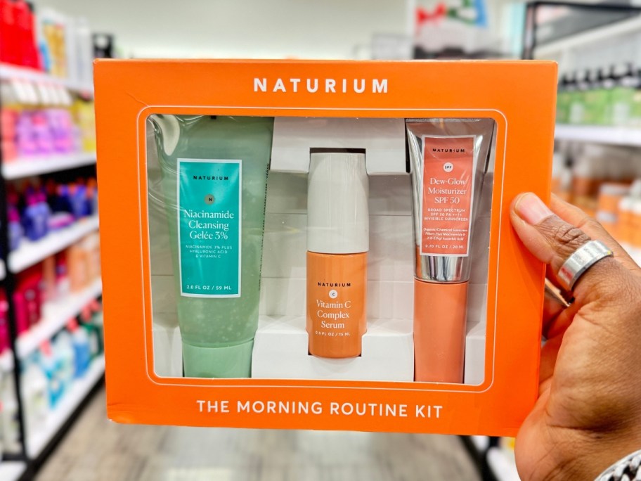 hand holding an orange box that's a Naturium The Morning Routine Gift Set