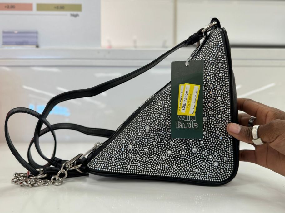 black triangle purse with rhinestone accents on shelf