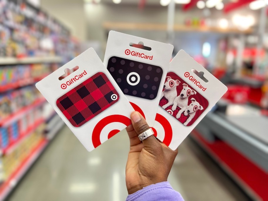 hand holding 3 different Target gift cards in the store