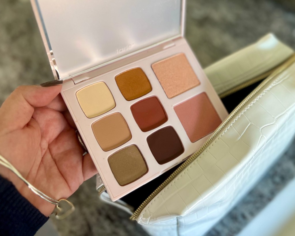 hand putting eyeshadow palette into makeup bag