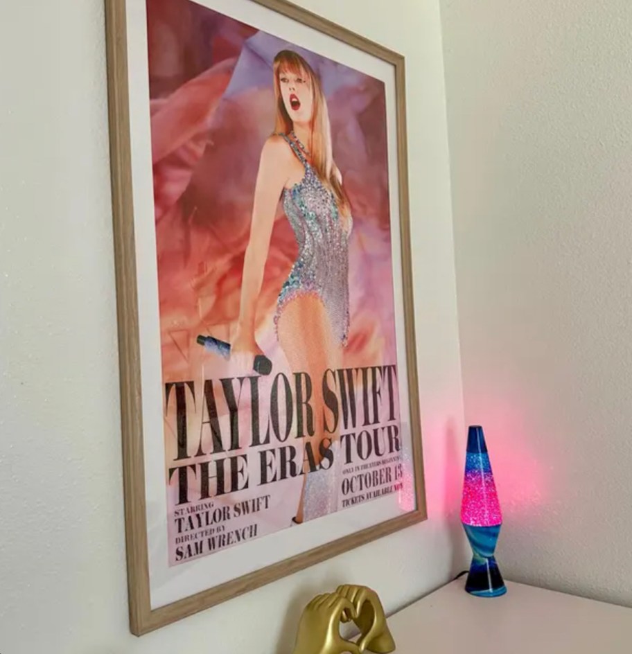 close up of taylor swift poster with frame on wall above lava lamp