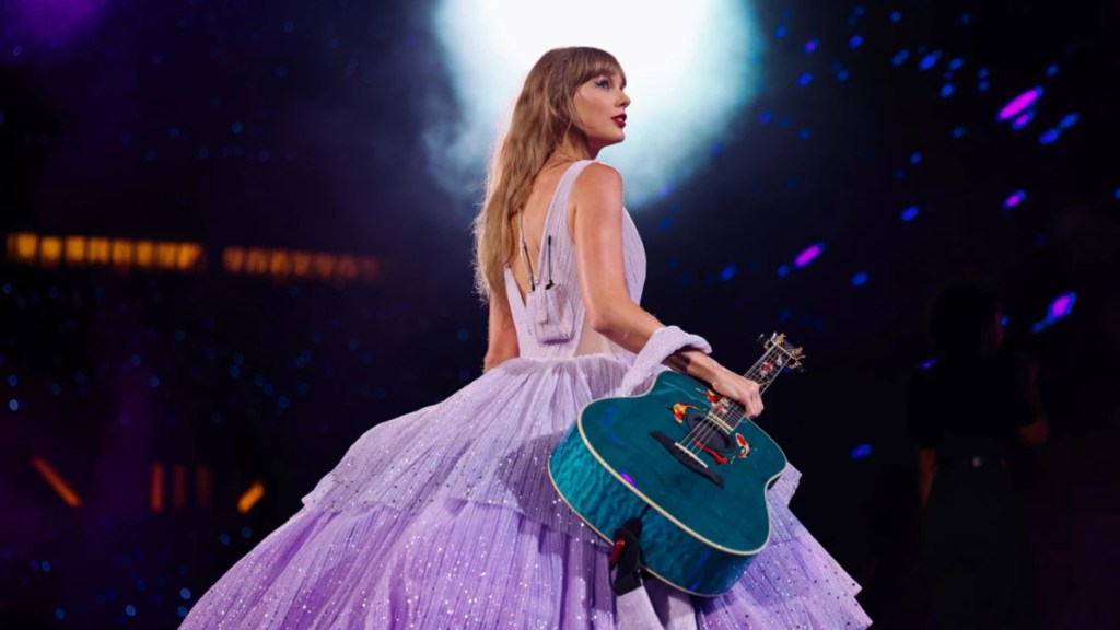 Taylor Swift in a purple dress holding a blue guitar