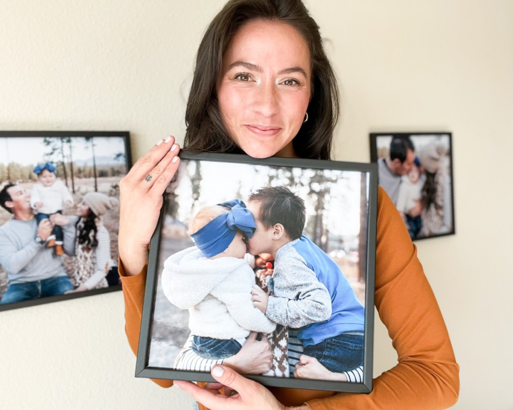 woman holding 12x12 black wood frame of babies kissing