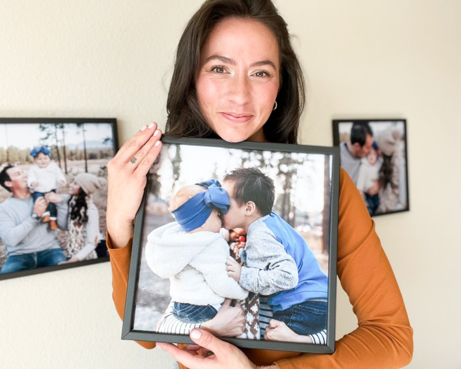 woman holding 12x12 black wood frame of babies kissing