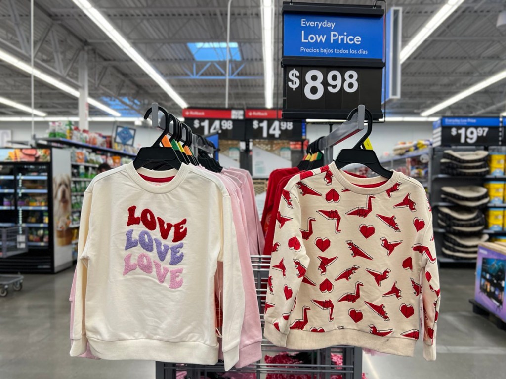 two kids valentines day sweatshirts hanging on rack in walmart