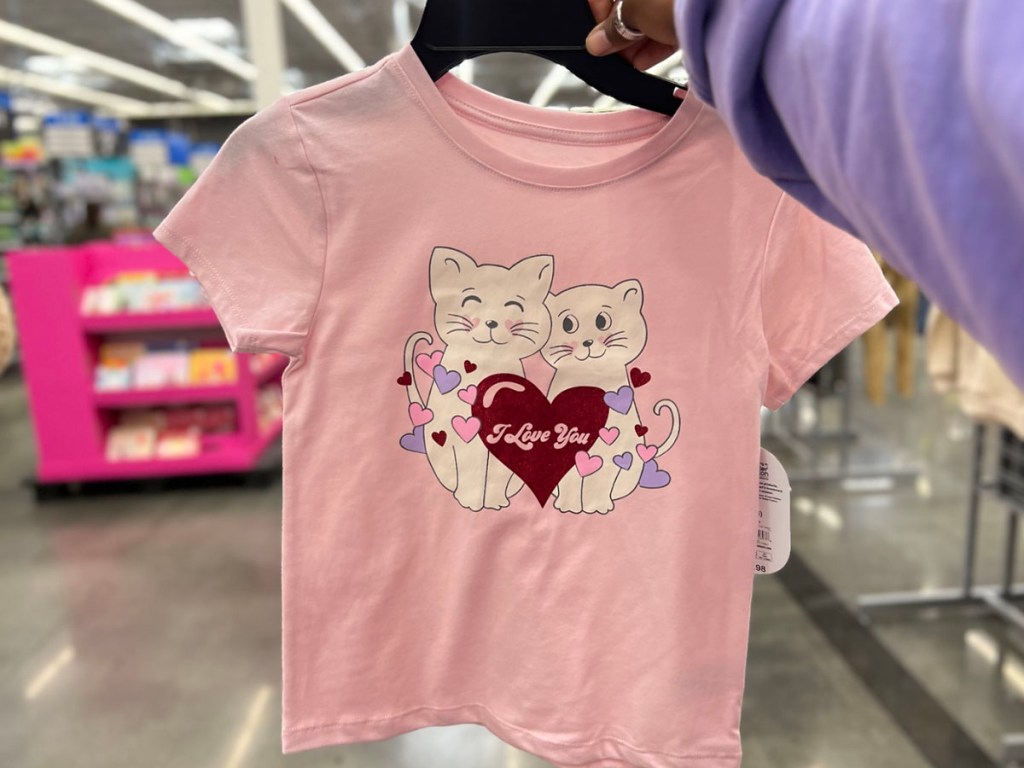 hand holding pink tee with cats and hearts on it