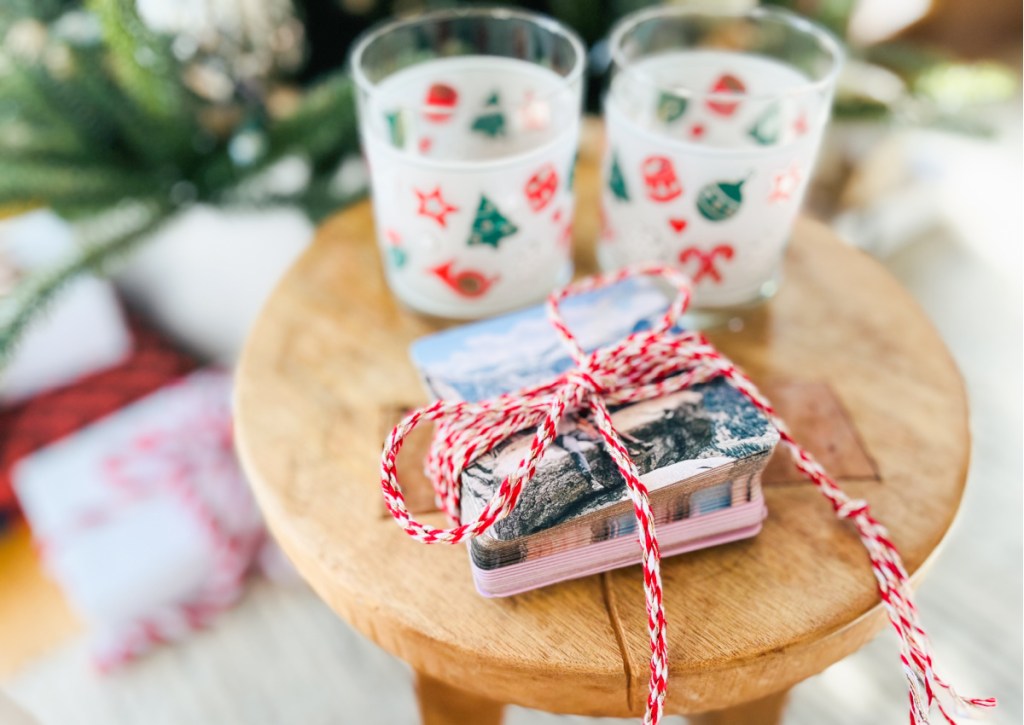 photo coasters in ribbon next to christmas glasses