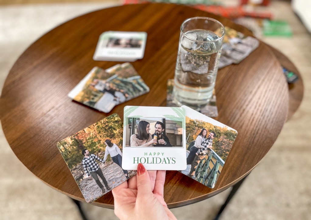 many photo coasters on wood table with glass of water