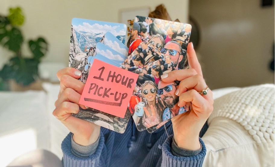 woman holding photo coasters in front of face