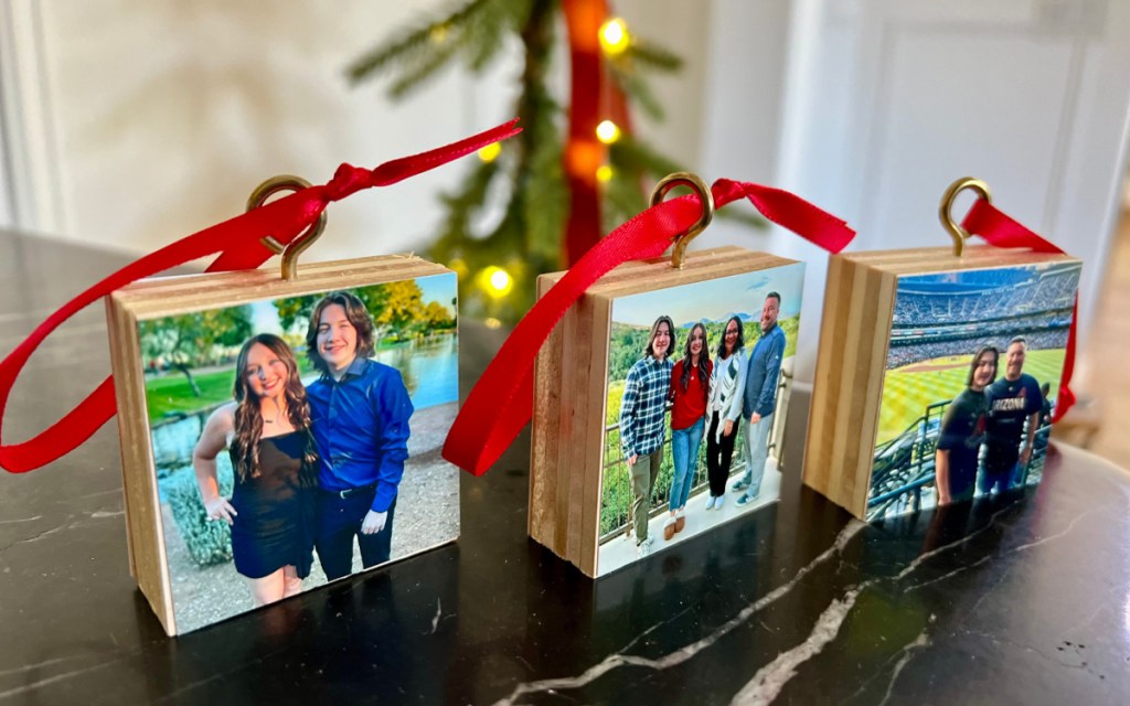 three wood photo ornaments with red ribbon on table