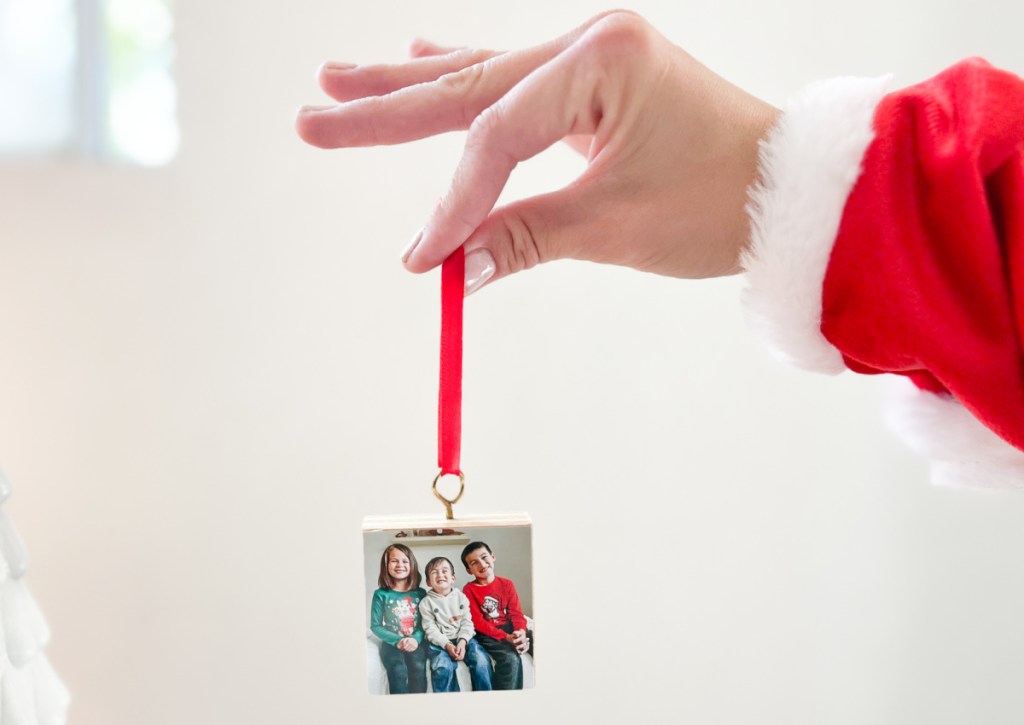 hand with santa shirt holding photo ornament