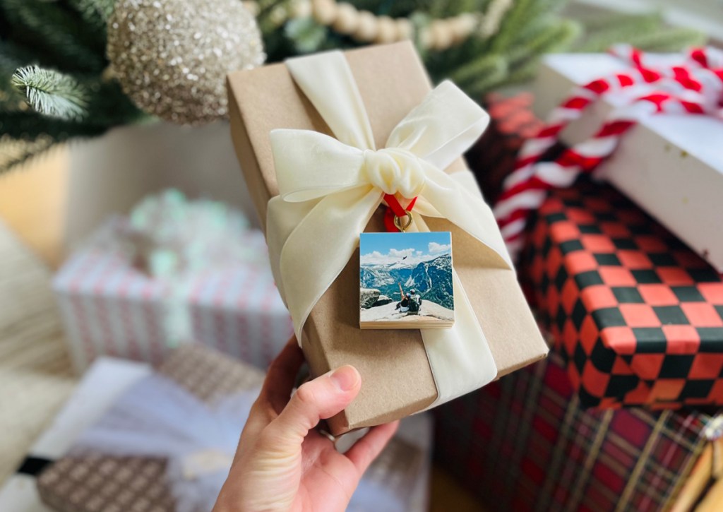 hand holding gift box with photo ornament as gift tag