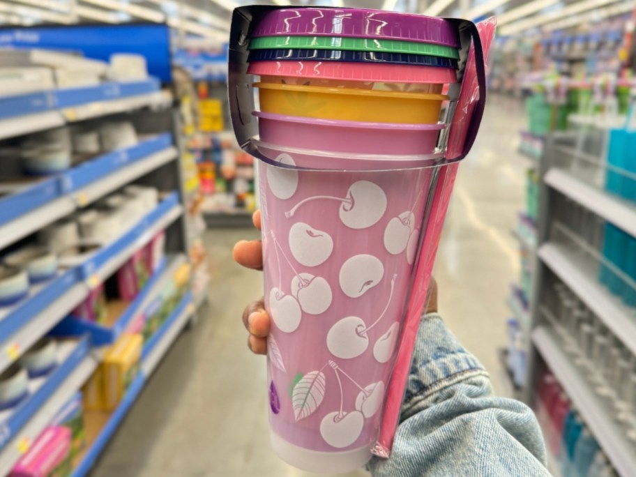 hand holding a 4 pack of colorful summer themed cups with lids and straws