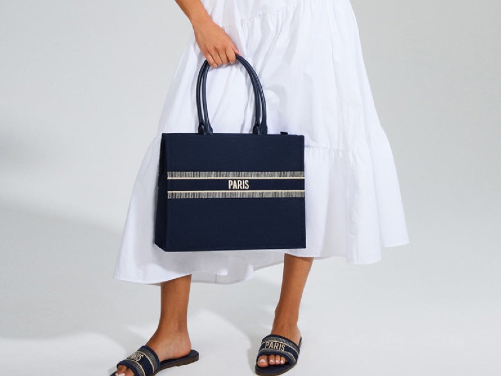 woman holding navy hand bag and matching sandals