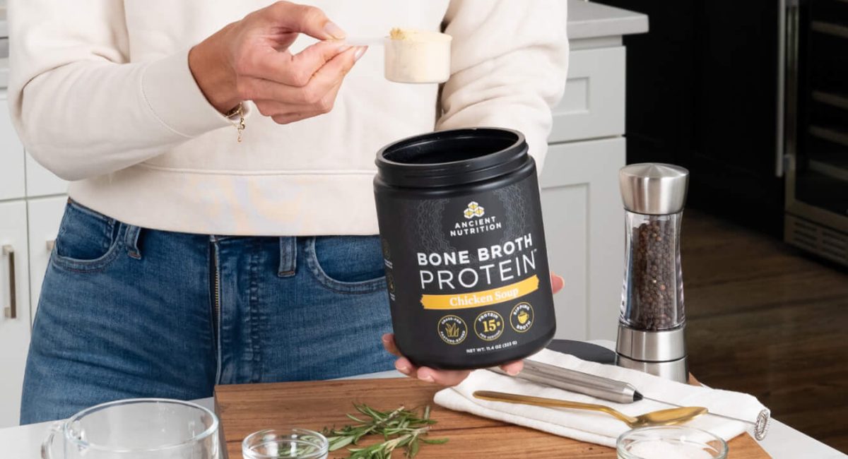 woman pouring bone broth protein in her kitchen