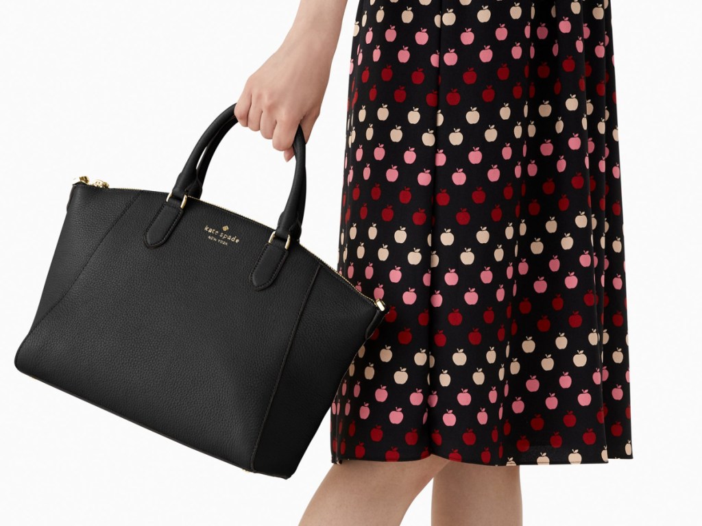 woman wearing a black and polka dot dress with a black handbag