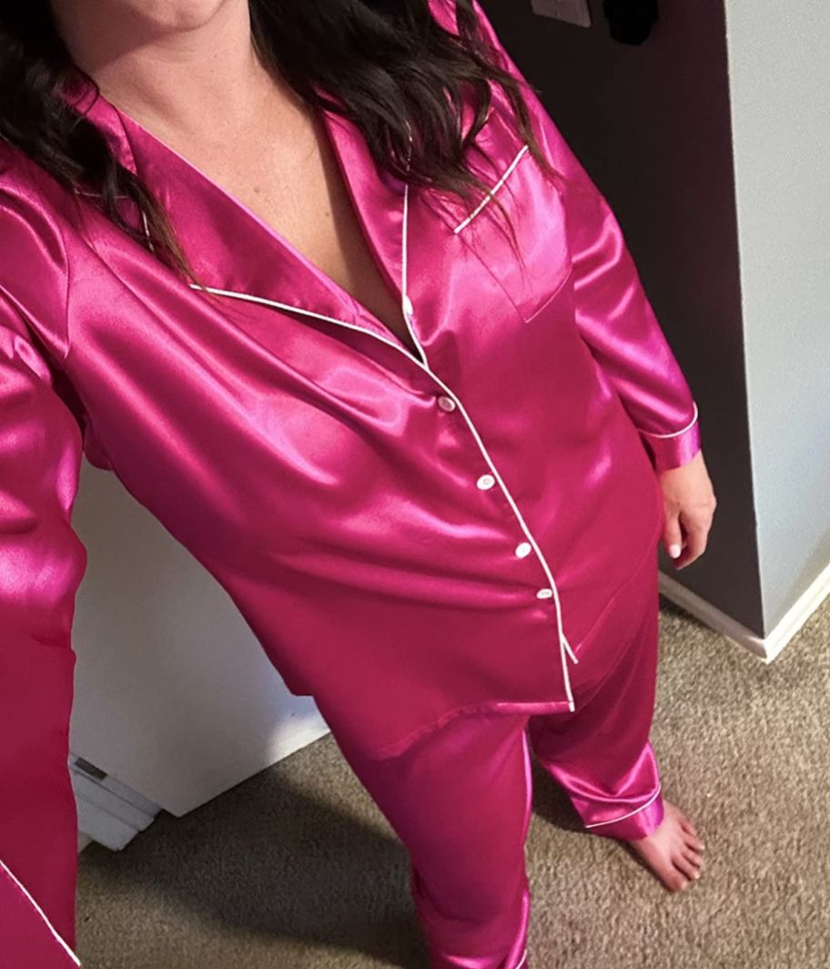 woman taking a selfie wearing a bright pink set of satin pajamas