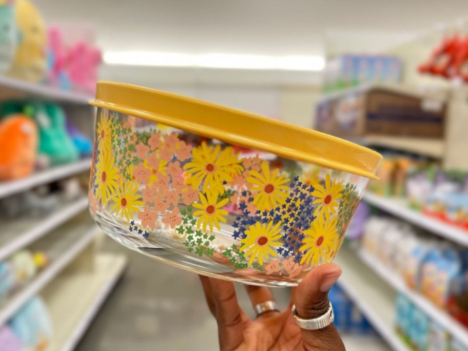 hand holding a glass food storage container with spring flower design and yellow lid
