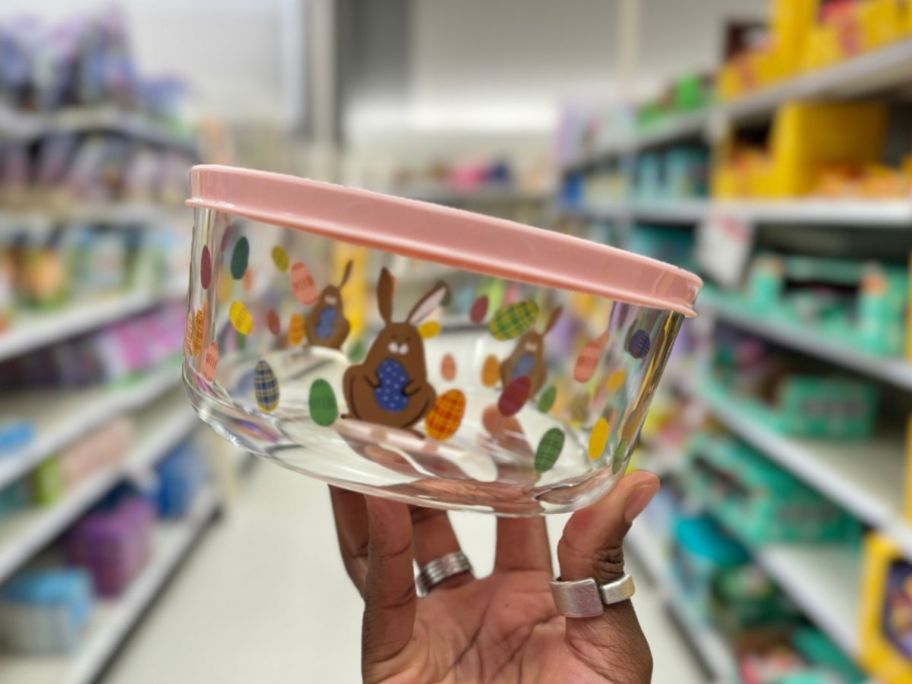 hand holding a glass food container with Easter bunny and eggs design on it and a pink lid