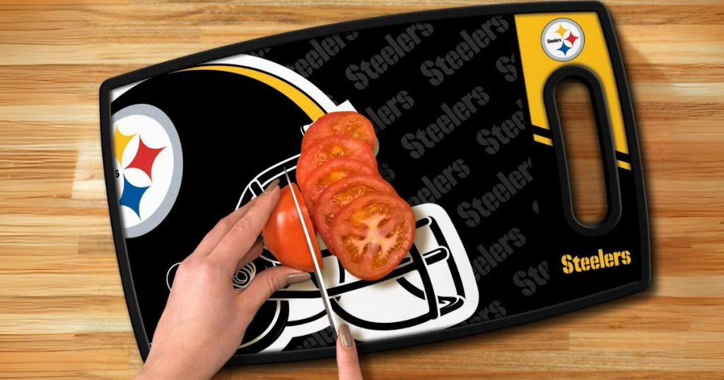 person's hands cutting a tomato on a Pittsburgh Steelers Cutting board