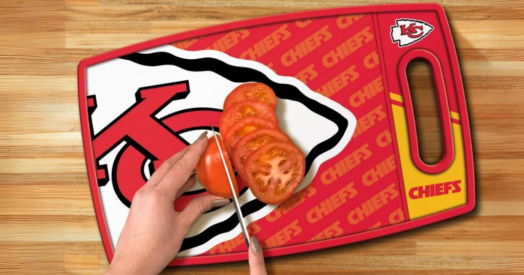 person's hands cutting a tomato on a Kansas City Chiefs Cutting board