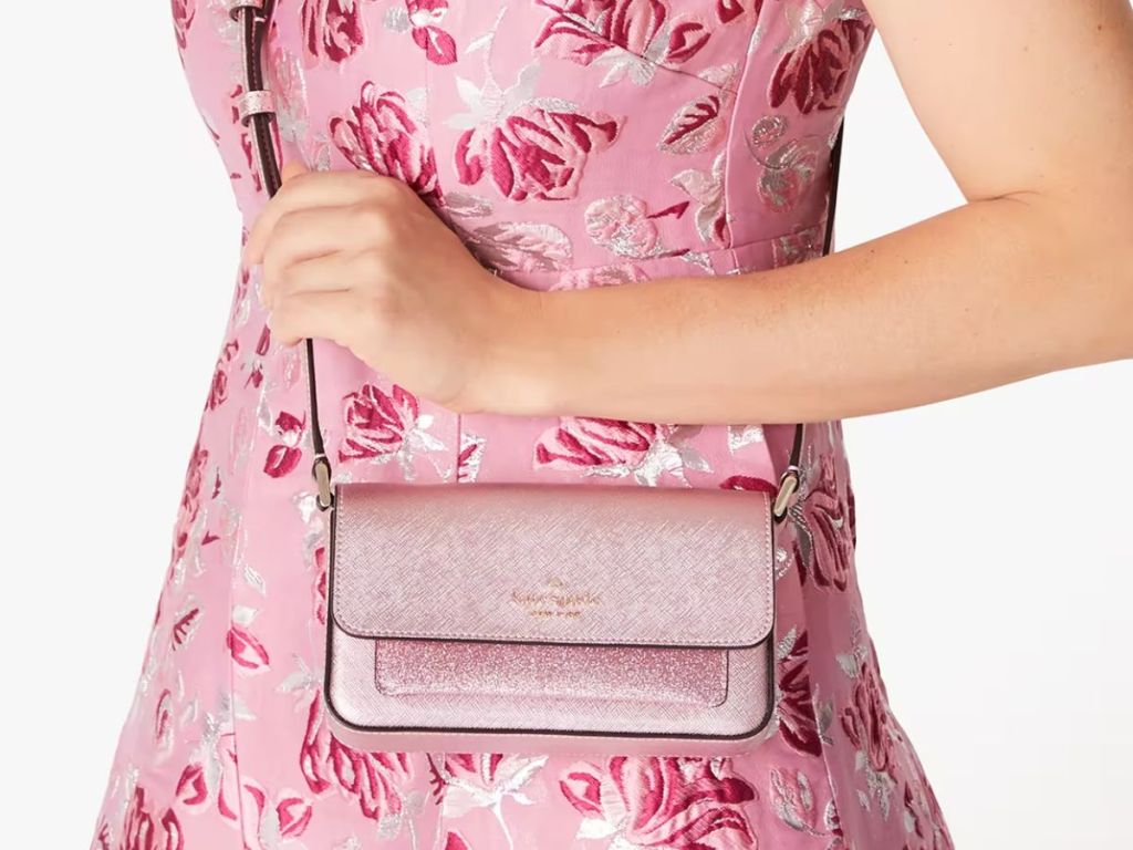 woman wearing a pink floral dress with a pink glittery Kate Spade Cross body purse