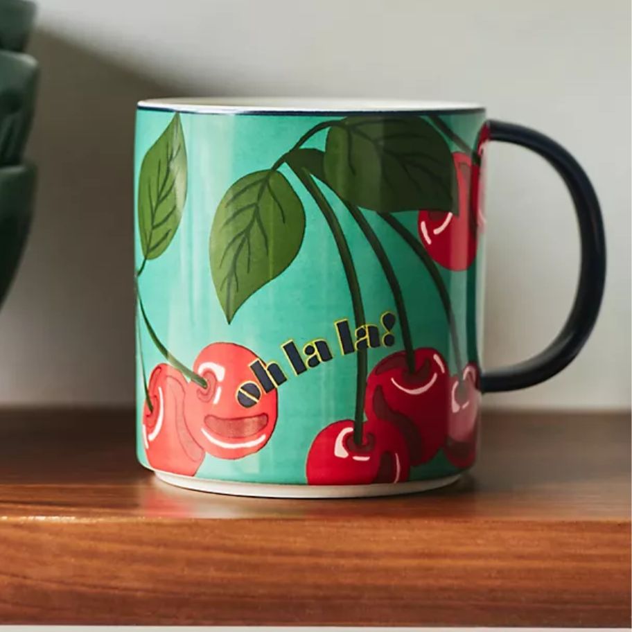 coffee mug with green background and cherries that says "Ooh la la"