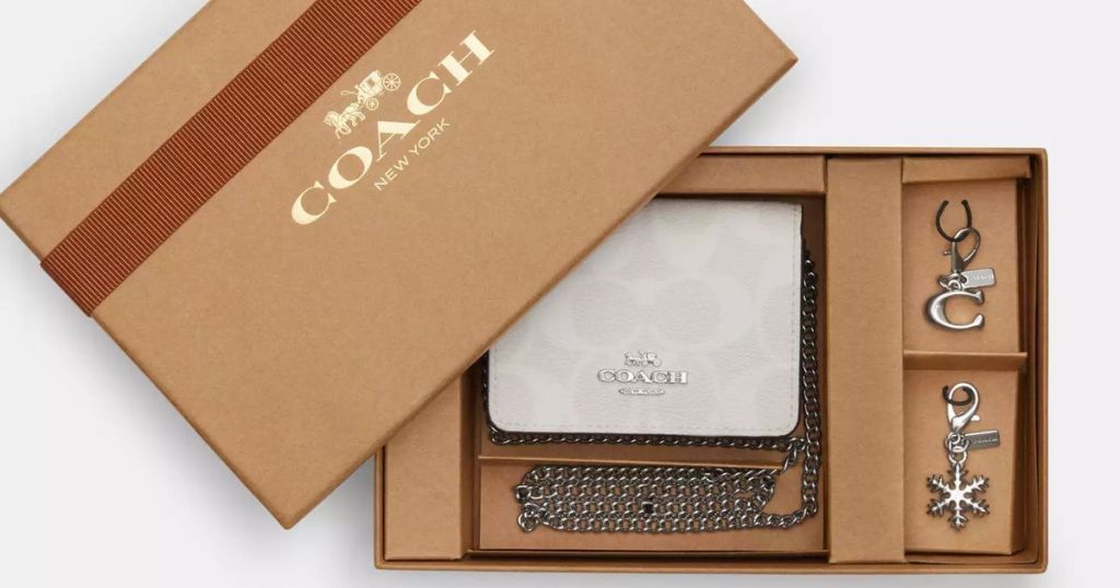 white Coach logo mini wallet with chain and accessories shown in a Coach gift box with the lid off to the side