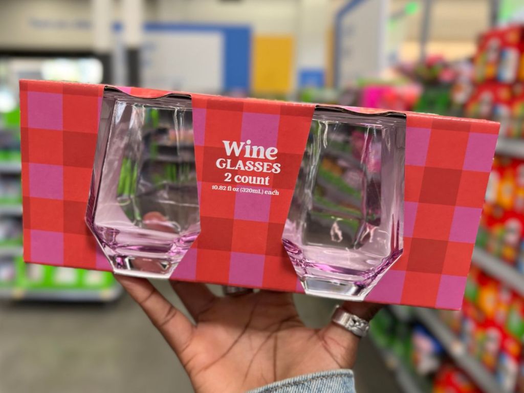 a womans hand displaying a 2 count pack pink stemless wine glasses in a red and pick box