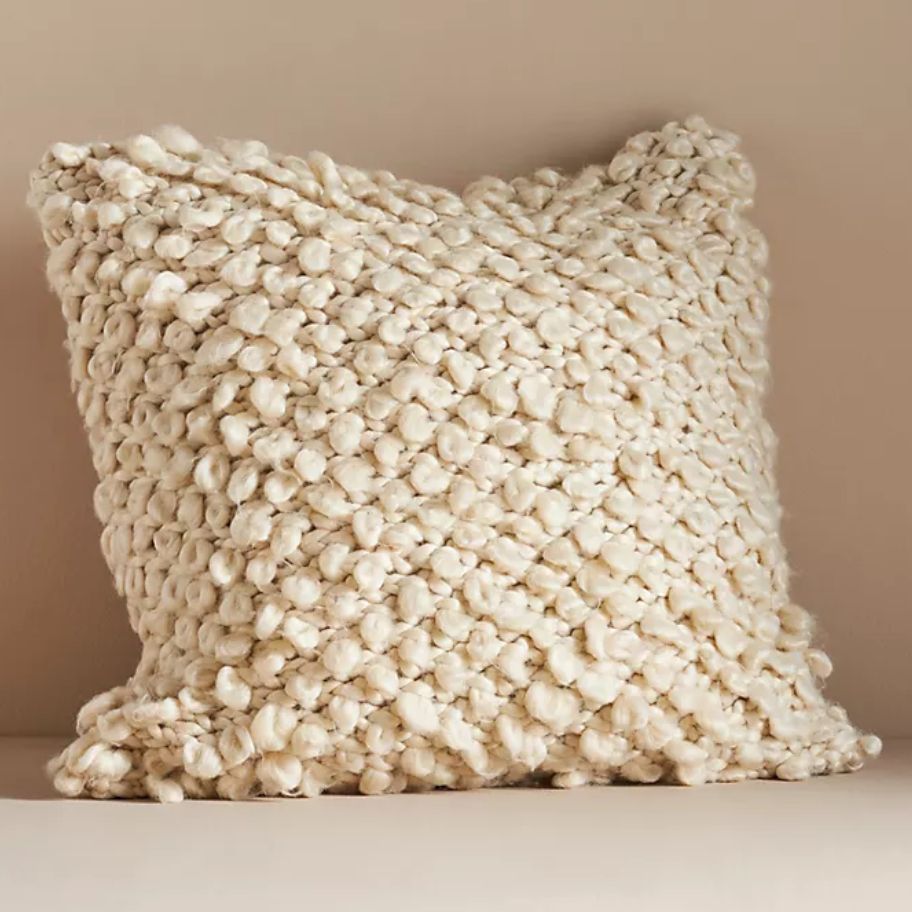 cream color large throw pillow sitting against a wall
