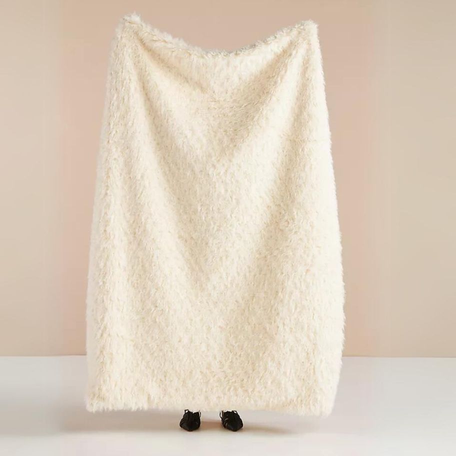 person holding a large off white color faux shearling blanket