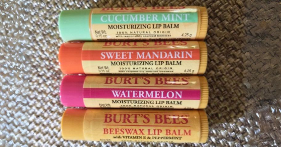 4 Burt's Bees Lip Balms laying on mat, original and fruity flavors