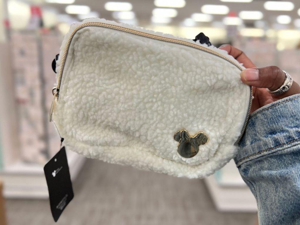 hand holding up a fuzzy fleece white and gold Minnie Mouse Belt Bag