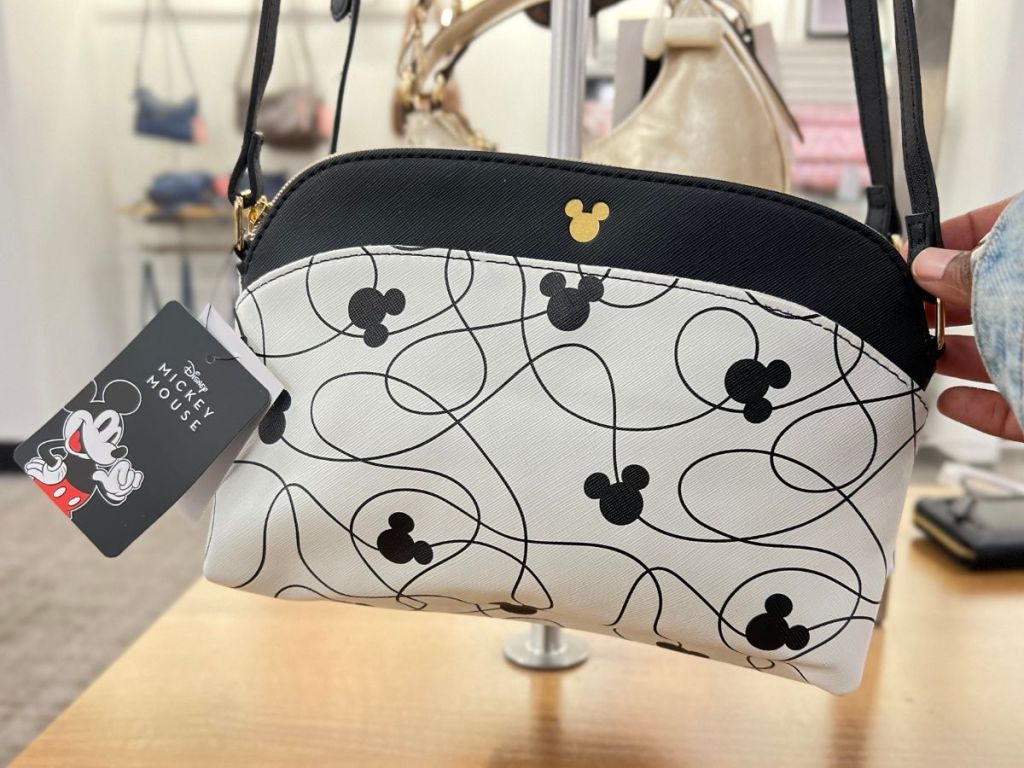 black cream and gold Disney Mickey Mouse crossbody purse hanging on display in store