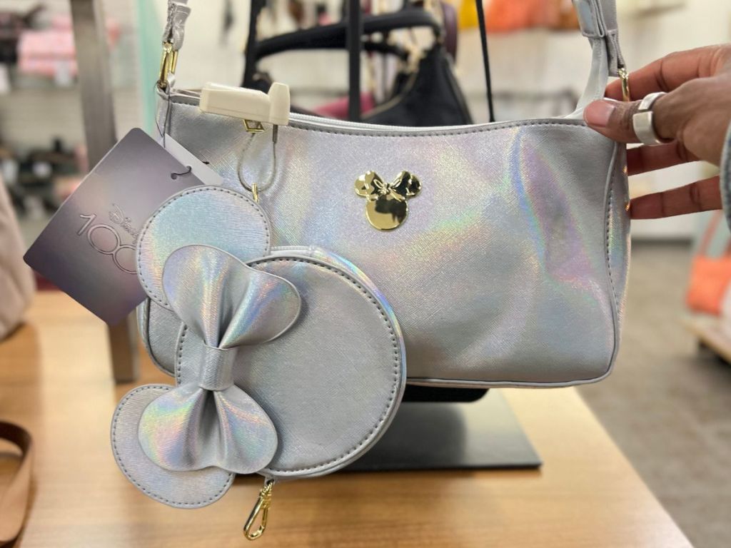 iridescent looking silver and gold Disney Minnie Mouse purse with zipper pouch hanging on display in store