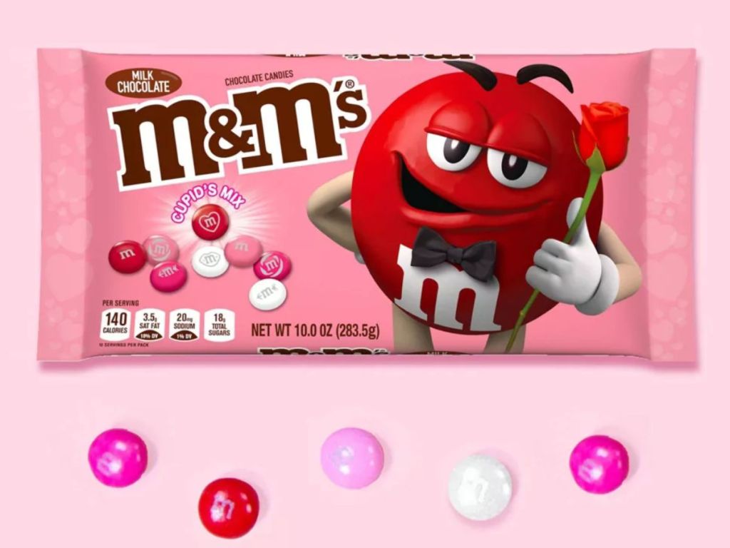 pink bag of Valentine's M&M's Cupid mix with individual M&M's laying around it